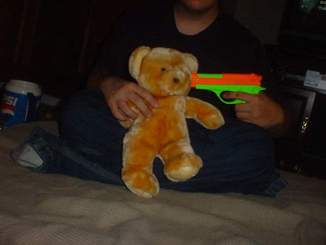 Jake holding a plastic gun to my teddy bear Bingo's head.