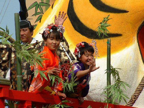 Girls waving from a float at Sakata festival.