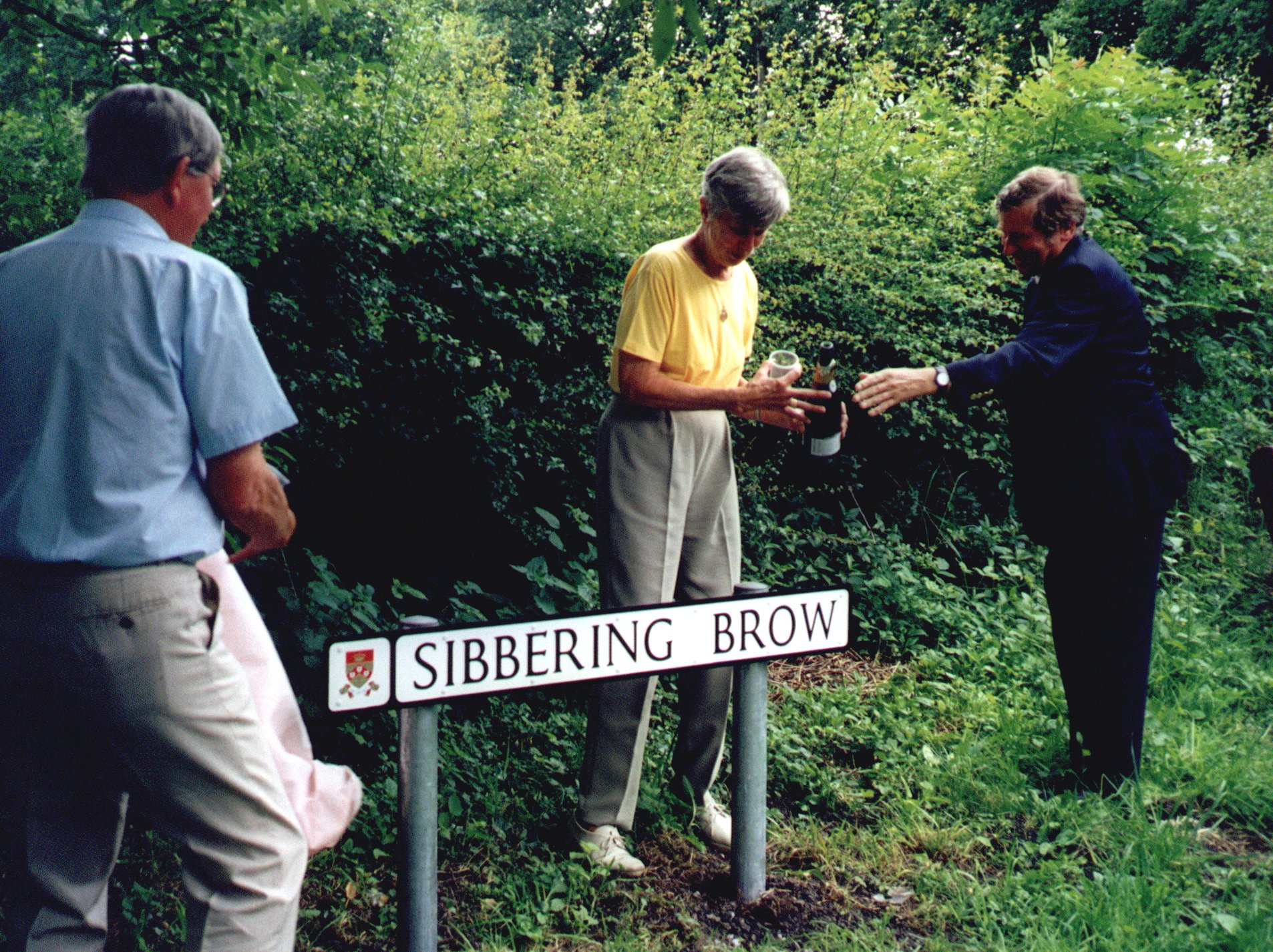 William and Dorothy Sibbering toast the unveiled road sign assisted  by Ralph Sibbring