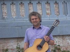 Siegfried Steinkogler vor einem Schloss in Gmunden, lachend, mit Gitarre ...