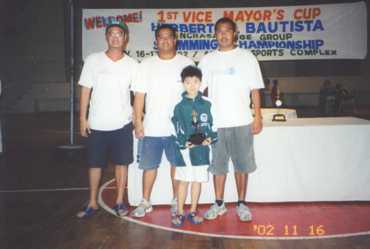 Coaches posing with swimmer and his trophy...