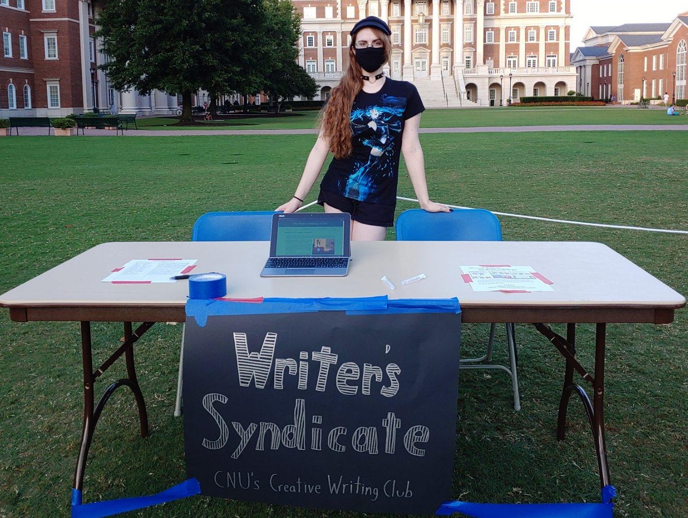 Heather standing at the outside club fair table for Writer's Syndicate.