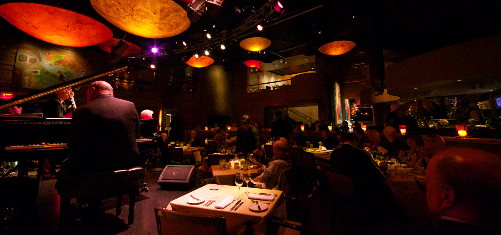 Image of Jazz Piano player on TOWN Cocktail Lounge stage with dining area in the background.