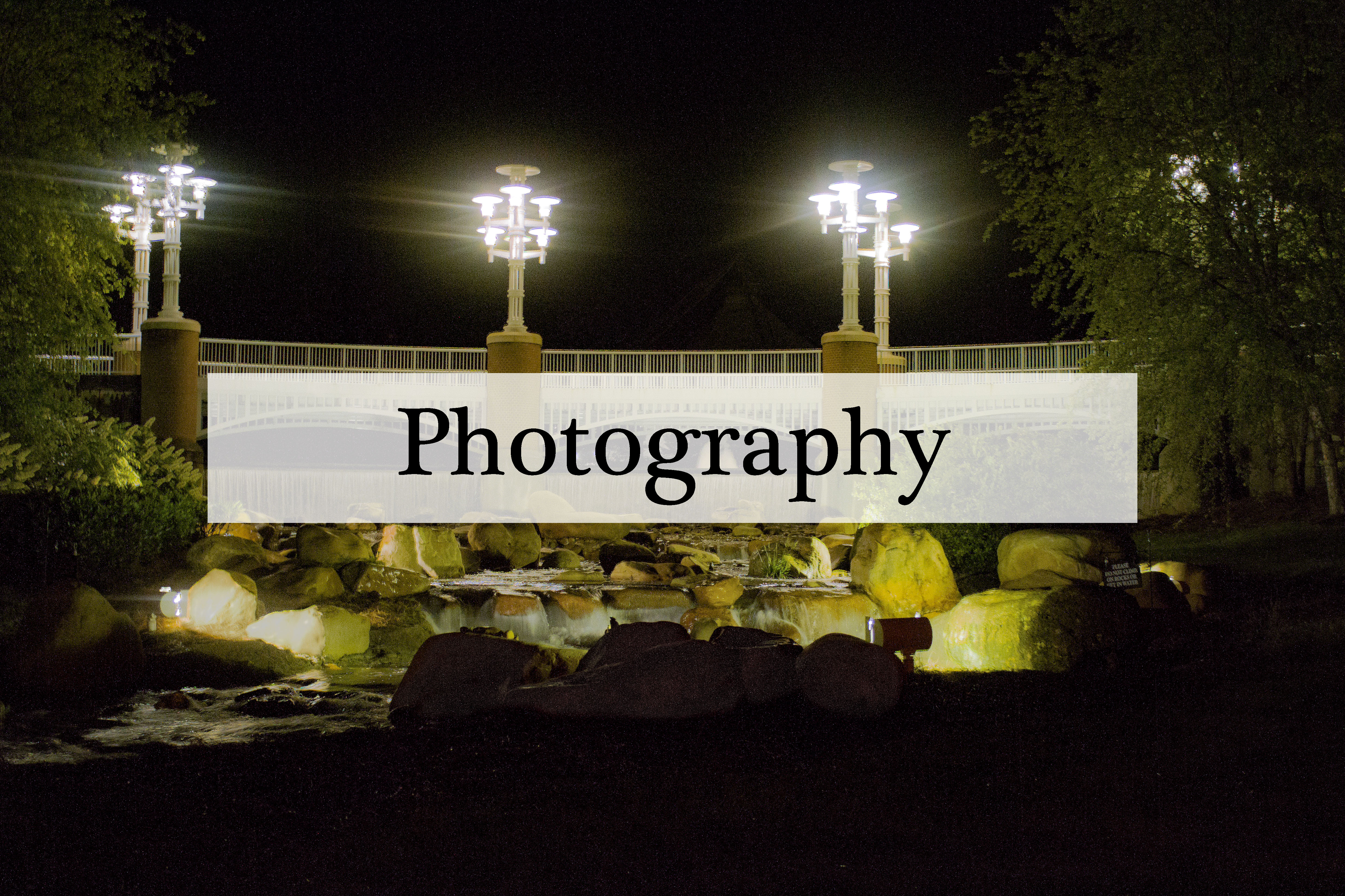 nightime scene with a lit-up bridge and waterfall