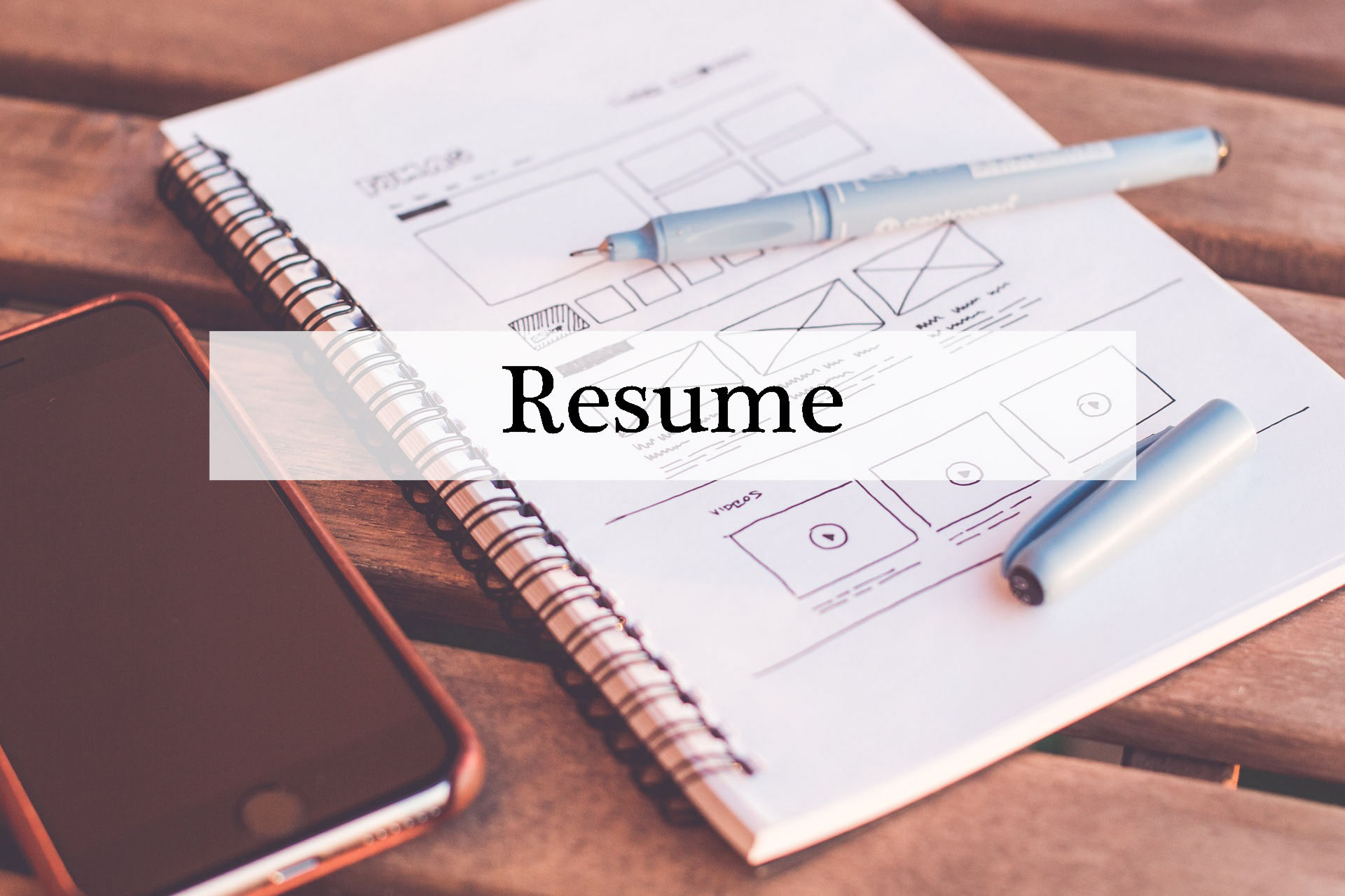 phone and paper laying on table with the word resume written on top