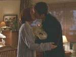 Mulder y Scully se besan mientras sostienen a su hijo William en brazos