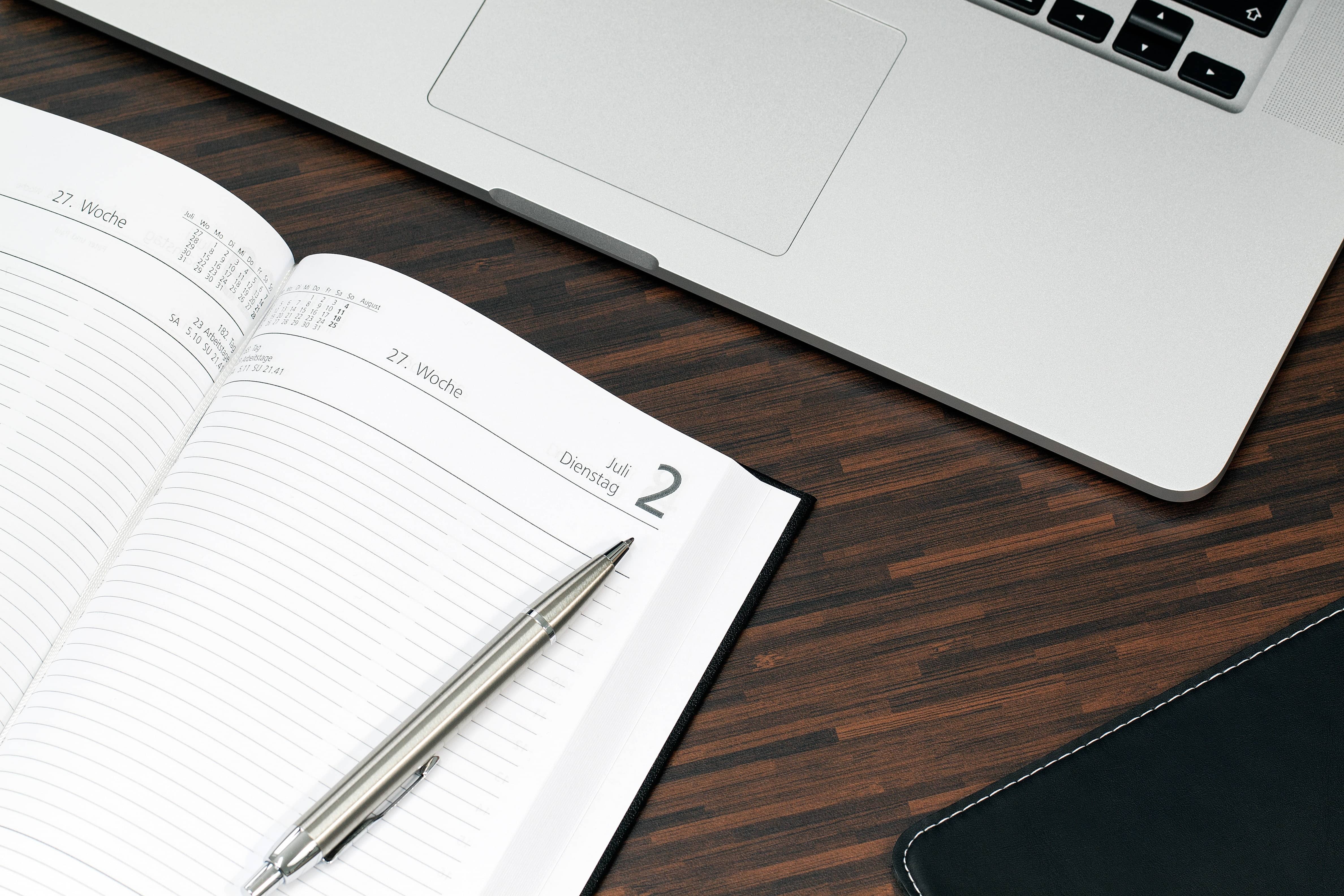 notebook with pen and laptop