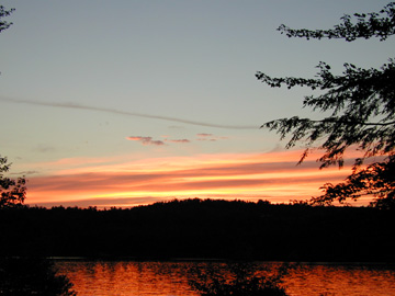 A fiery red sunset reflected on a lake