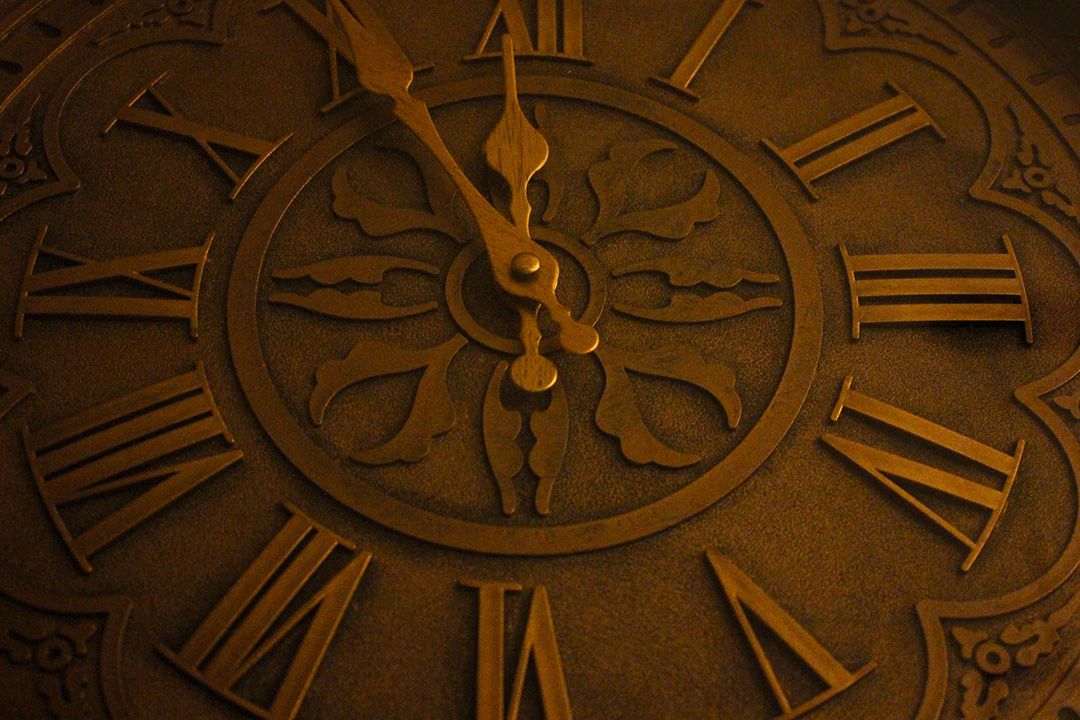 close up picture of a brown clock with roman numerals