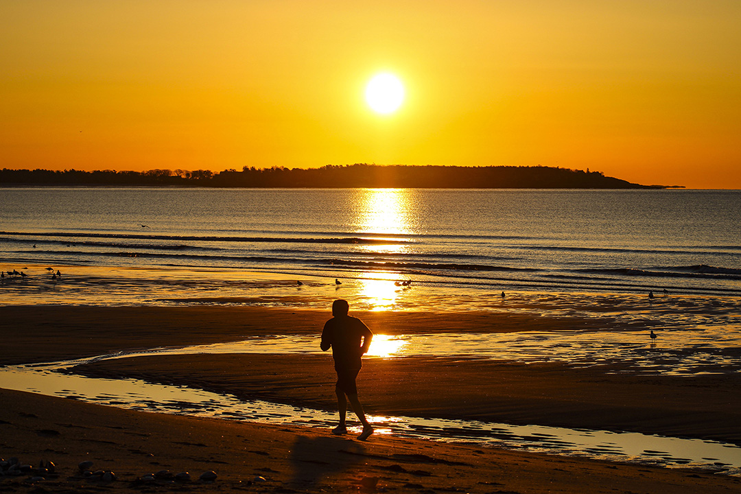 Man jogging on a beach at sunset