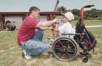 Archery instructor Scott McMain (left) teaches Corey Talaksen, 8, how to shoot a bow and arrow at 'A Day at the Range' event for people with disabilities.